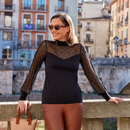 Mujer con blusa negra semitransparente de lunares y pantalón marrón poliìel-Janira